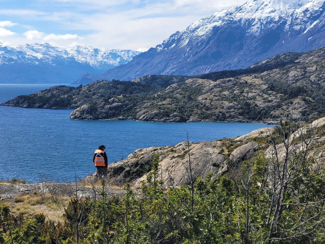 Topógrafo con GNSS sobre roca frente al lago